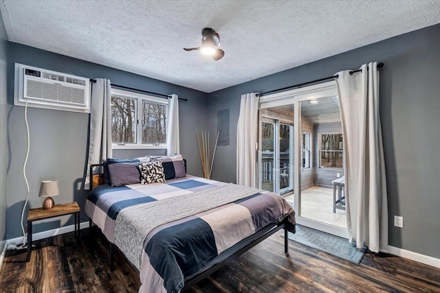 bedroom featuring an AC wall unit, a textured ceiling, wood finished floors, access to outside, and baseboards