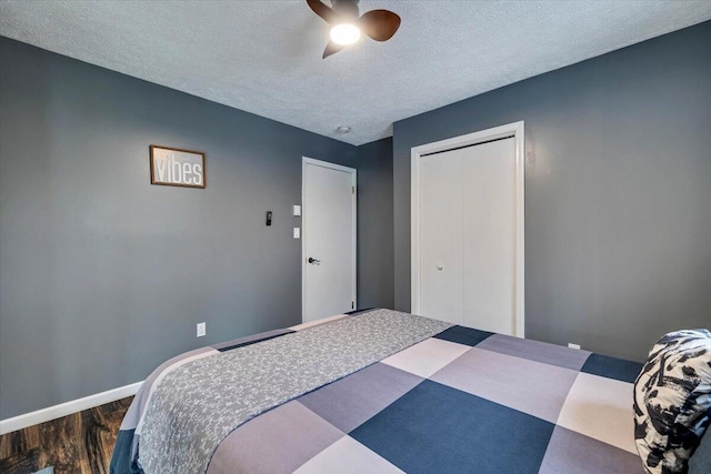 bedroom with dark wood finished floors, a closet, a ceiling fan, a textured ceiling, and baseboards