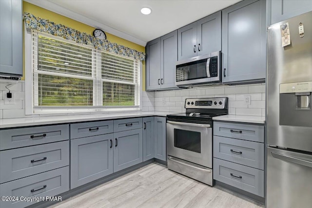 kitchen with decorative backsplash, appliances with stainless steel finishes, and gray cabinetry