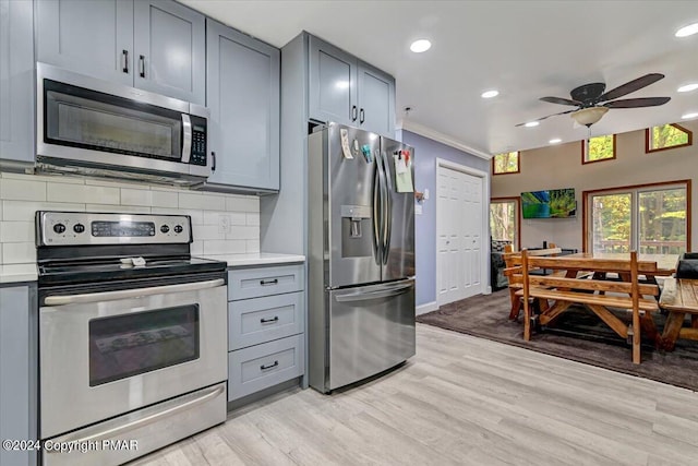 kitchen with stainless steel appliances, decorative backsplash, gray cabinets, and light countertops