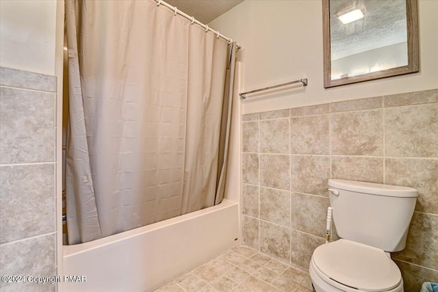 bathroom featuring shower / bath combination with curtain, a textured ceiling, tile walls, and toilet