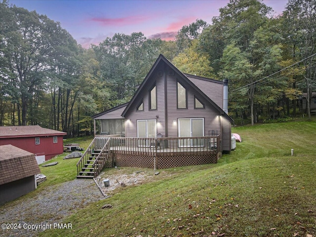 back of property featuring a yard, a forest view, and a wooden deck