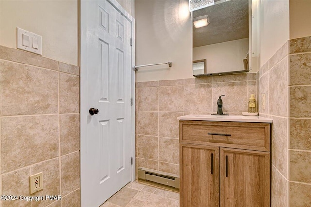 bathroom featuring vanity, tile walls, baseboard heating, and a textured ceiling