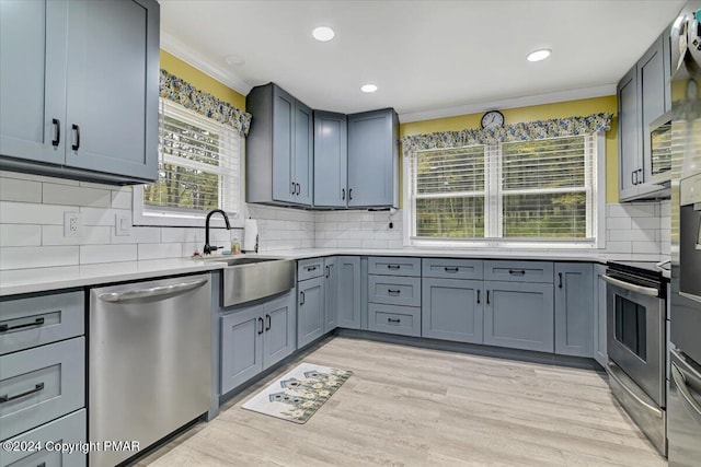 kitchen with a sink, stainless steel appliances, light wood-style floors, and light countertops