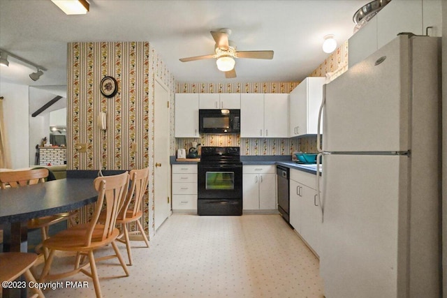 kitchen with light floors, white cabinets, black appliances, dark countertops, and wallpapered walls