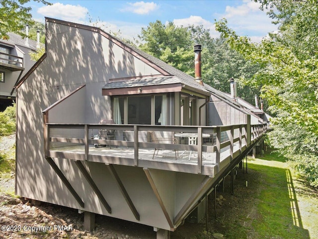 back of property with a shingled roof and a wooden deck