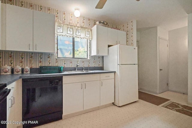 kitchen featuring a sink, black dishwasher, freestanding refrigerator, dark countertops, and wallpapered walls