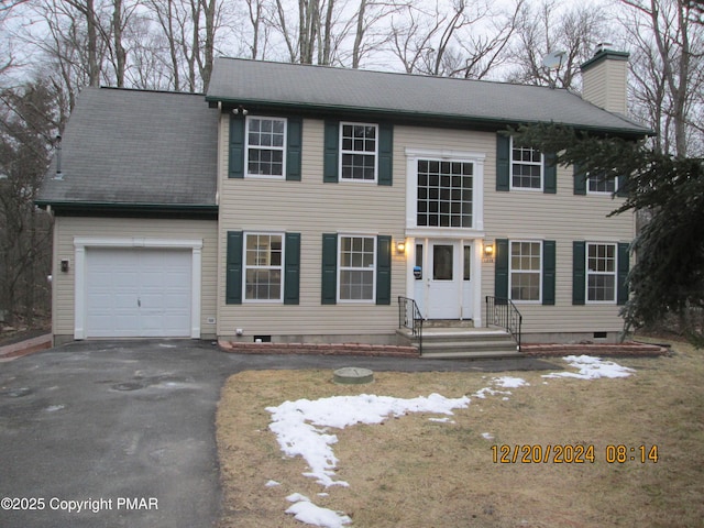 view of front of house with aphalt driveway, a chimney, and an attached garage