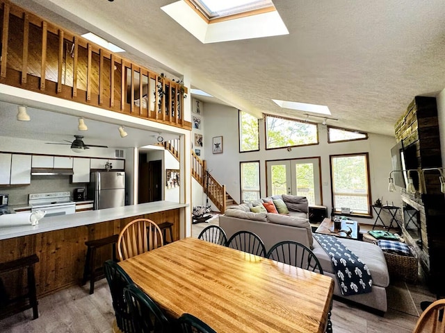 251 Dorchester Dr, Bushkill, PA 18324 - dining space featuring a skylight, light wood-type flooring, a textured ceiling, stairway, and vaulted ceiling