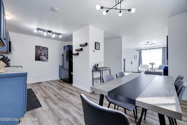 dining room featuring light wood-style flooring, baseboards, and an inviting chandelier