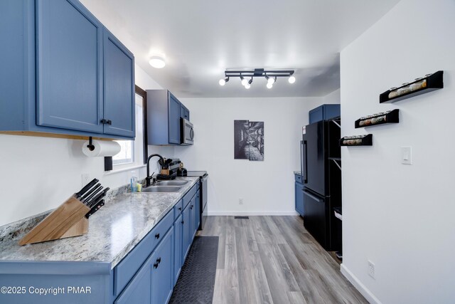 kitchen with range with electric stovetop, stainless steel microwave, freestanding refrigerator, and blue cabinets