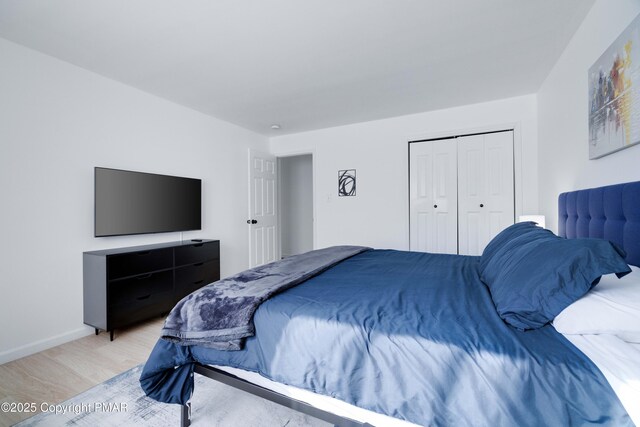 bedroom featuring baseboards, a closet, and light wood-style floors