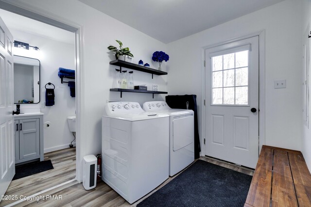 laundry area with laundry area, baseboards, washer and dryer, and wood finished floors