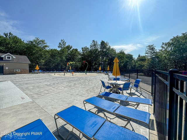 view of patio featuring playground community and fence