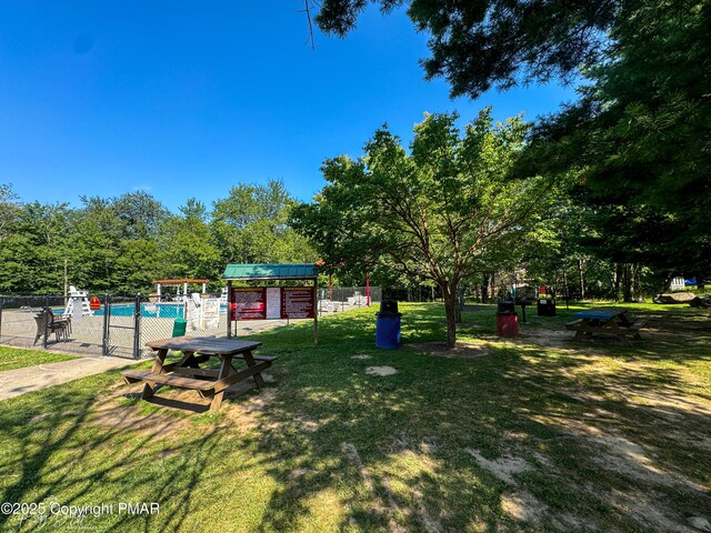 view of community with a swimming pool, fence, and a yard