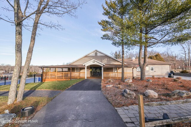 view of front of house with driveway, fence, a porch, and a front yard