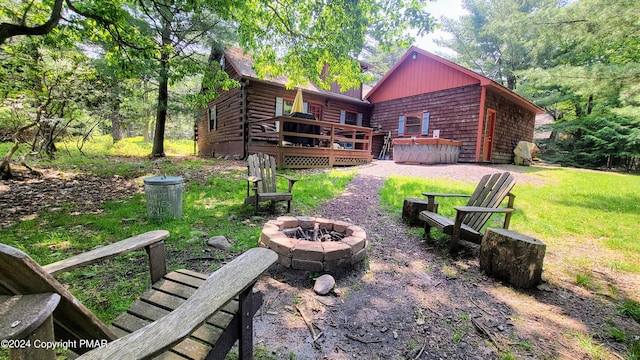 back of property with log exterior, a fire pit, a yard, and a wooden deck