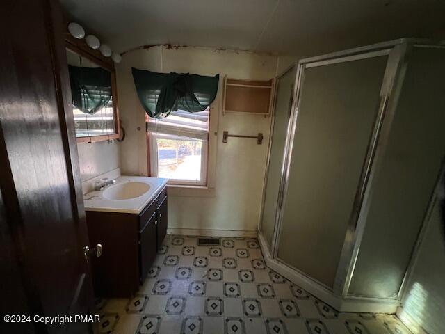 full bathroom with a stall shower, vanity, and tile patterned floors