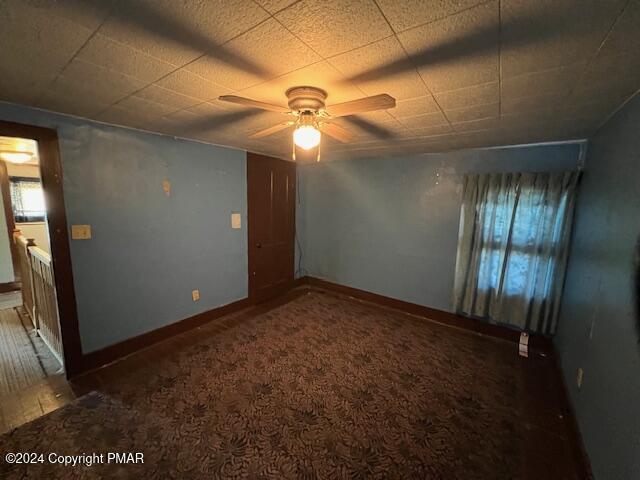 carpeted empty room featuring ceiling fan and baseboards