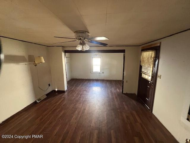 empty room with visible vents, dark wood finished floors, and a ceiling fan