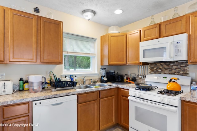 kitchen featuring a textured ceiling, white appliances, a sink, light countertops, and decorative backsplash