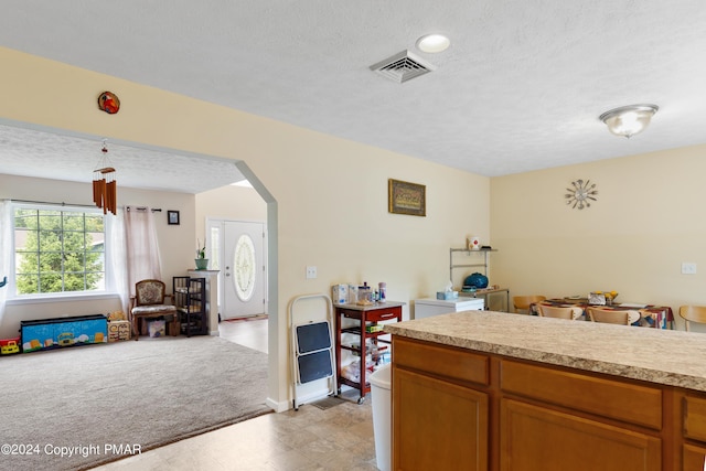 kitchen with light carpet, visible vents, arched walkways, open floor plan, and light countertops