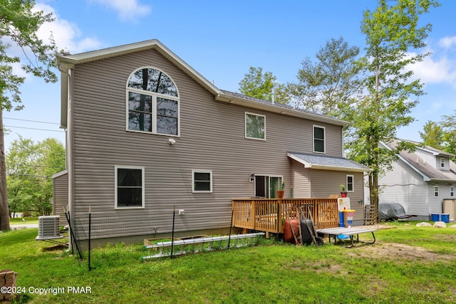 rear view of property featuring a lawn, a deck, and cooling unit