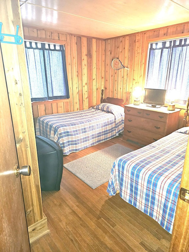 bedroom featuring multiple windows, wood walls, and wood finished floors