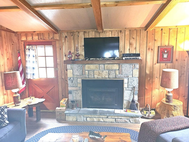 living area featuring beam ceiling, wood finished floors, a fireplace, and wood walls