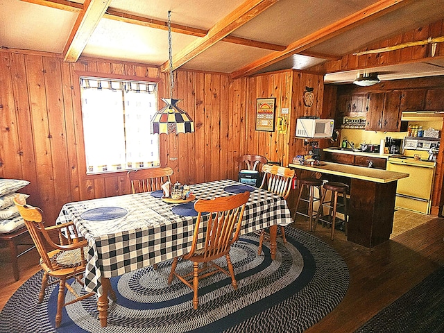 dining area featuring beam ceiling and wood walls