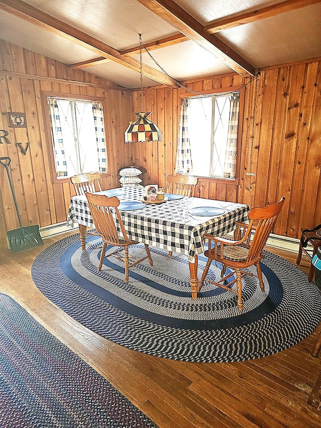 dining area featuring beam ceiling, a healthy amount of sunlight, and hardwood / wood-style flooring