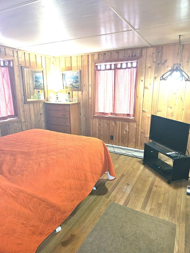 bedroom featuring hardwood / wood-style floors, wooden walls, and a baseboard radiator