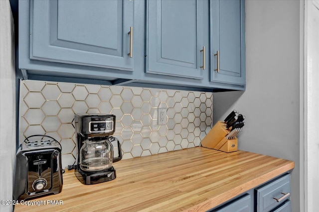 details featuring blue cabinets, butcher block counters, and tasteful backsplash