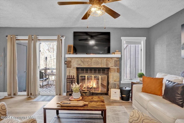 living area featuring a fireplace, a textured ceiling, and wood finished floors