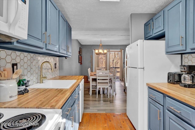 kitchen with white appliances, butcher block counters, and blue cabinetry