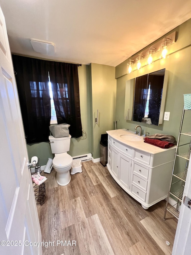 bathroom with baseboards, toilet, wood finished floors, vanity, and a baseboard radiator