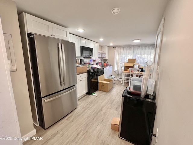 kitchen with light wood-type flooring, black appliances, dark countertops, white cabinetry, and baseboards