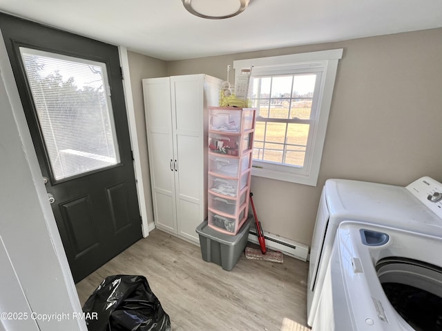 laundry room featuring baseboards, washing machine and clothes dryer, cabinet space, a baseboard heating unit, and light wood-type flooring