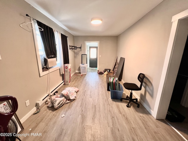 workout area with baseboards, baseboard heating, and wood finished floors