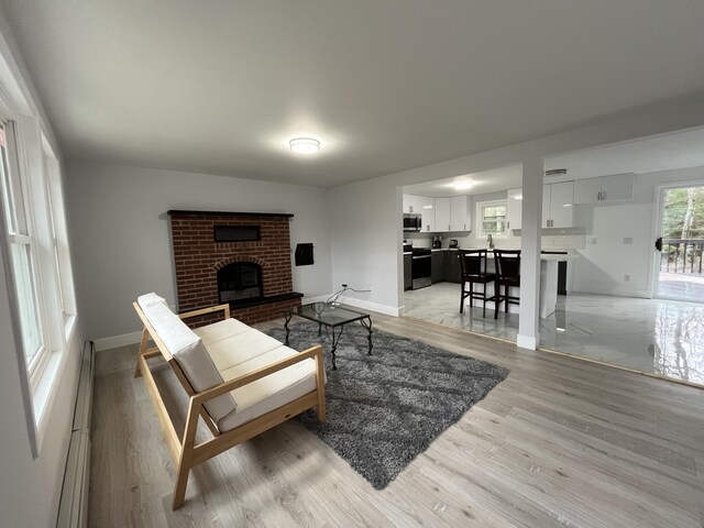 3015 Mountain Ter, Stroudsburg, PA 18360 - living room featuring light wood-type flooring, a brick fireplace, and a baseboard heating unit