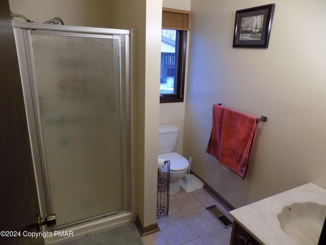 bathroom with an enclosed shower, vanity, tile patterned flooring, and toilet