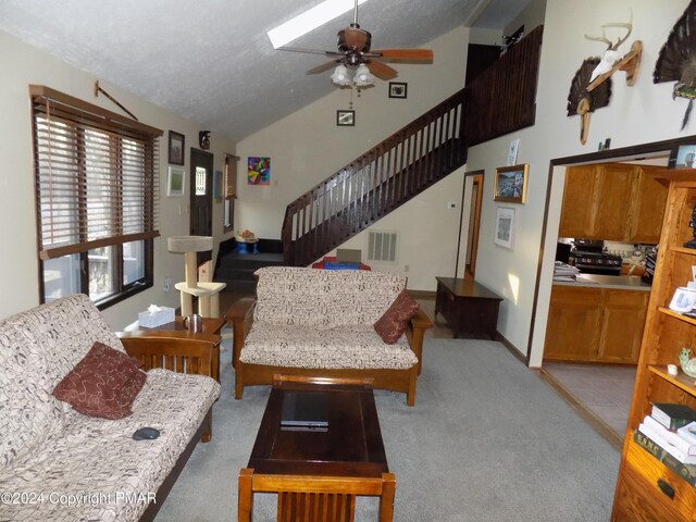 carpeted living room with vaulted ceiling, a textured ceiling, and ceiling fan