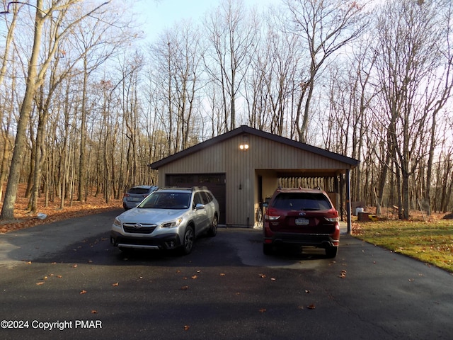 view of front of house featuring aphalt driveway, a detached garage, and an outbuilding