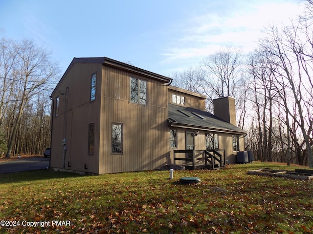 view of side of property featuring cooling unit, a chimney, and a yard