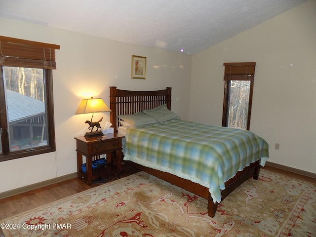 bedroom featuring vaulted ceiling, baseboards, and wood finished floors