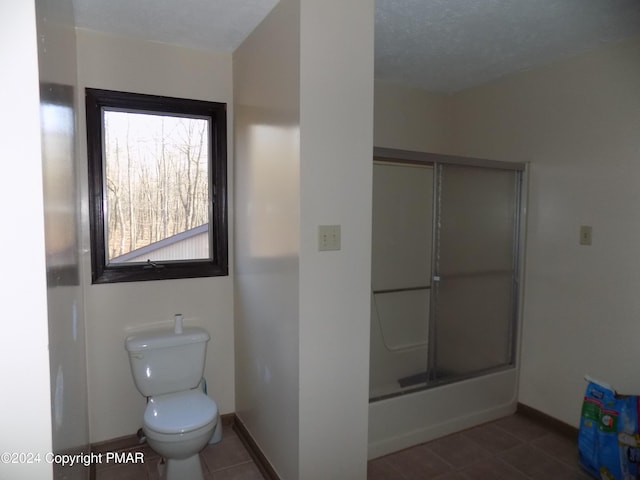 bathroom featuring tile patterned floors, shower / bath combination with glass door, and toilet