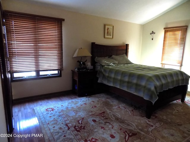 bedroom with multiple windows, baseboards, lofted ceiling, and wood finished floors