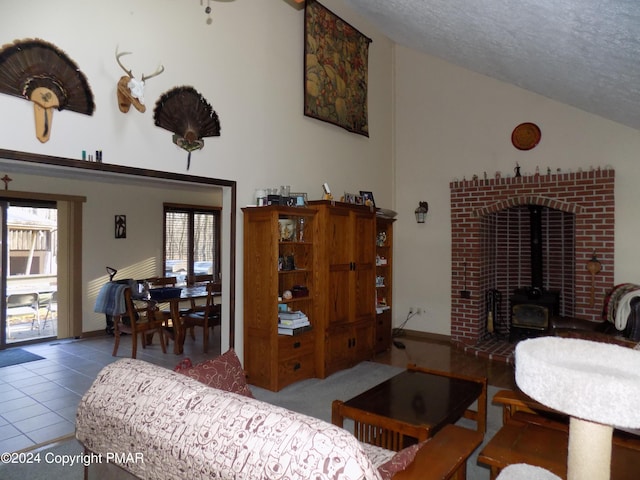 living room with high vaulted ceiling, a wood stove, tile patterned floors, and a textured ceiling