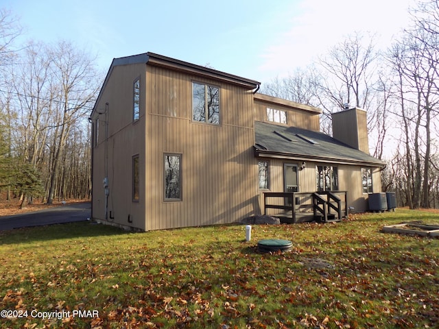 back of property with central AC unit and a yard