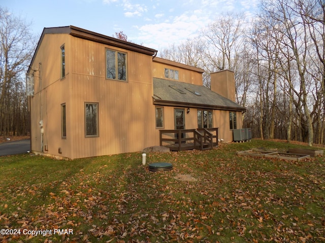 rear view of property featuring central AC unit and a yard